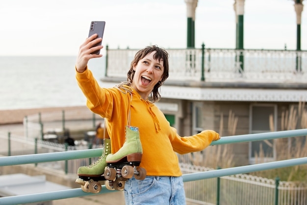 Frau mit Rollschuhen, die mit ihrem Smartphone im Freien ein Selfie macht