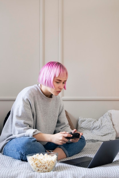 Kostenloses Foto frau mit rosa haaren, die mit einem joystick auf dem laptop spielen