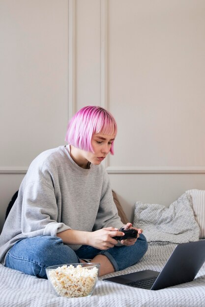 Frau mit rosa Haaren, die mit einem Joystick auf dem Laptop spielen