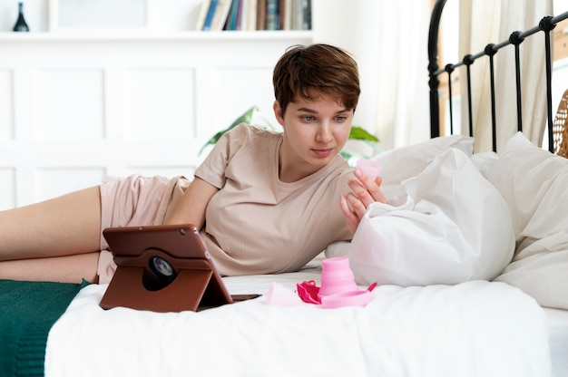 Kostenloses Foto frau mit rosafarbener menstruationstasse im bett