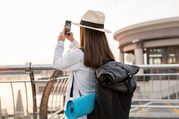 Frau mit Rucksack, die Fotos während des Reisens macht