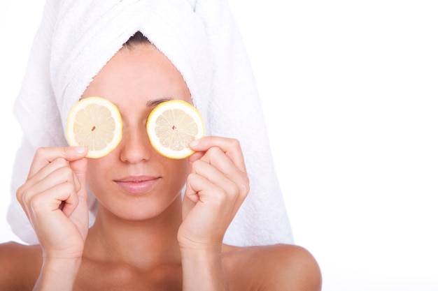 Frau mit sauberem Gesicht hält zwei Zitronenscheiben