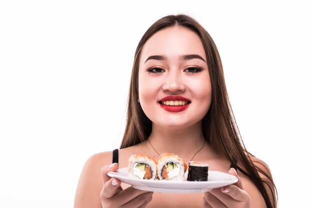 Frau mit schwarzen Haaren und roten Lippen schmecken Sushi-Rollen, die hölzerne Essstäbchen in ihrer Hand halten