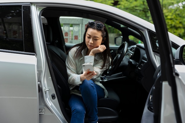 Frau mit Smartphone im Elektroauto