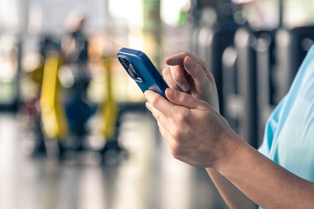 Frau mit Smartphone im Fitnessstudio in der Nähe