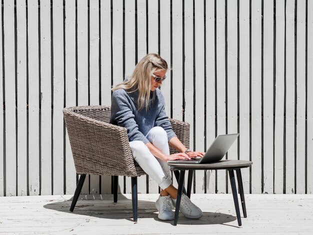 Frau mit Sonnenbrille, die draußen am Laptop arbeitet