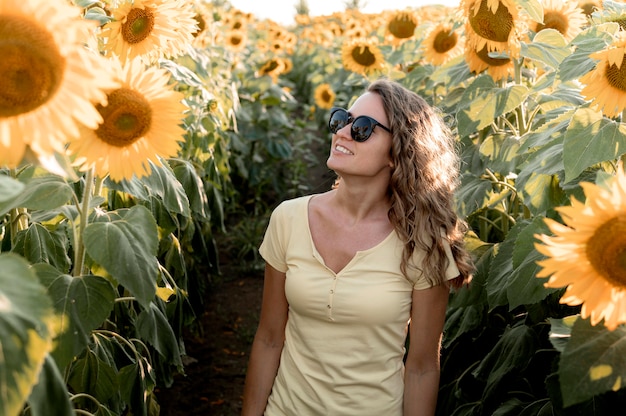 Frau mit Sonnenbrille im Sonnenblumenfeld