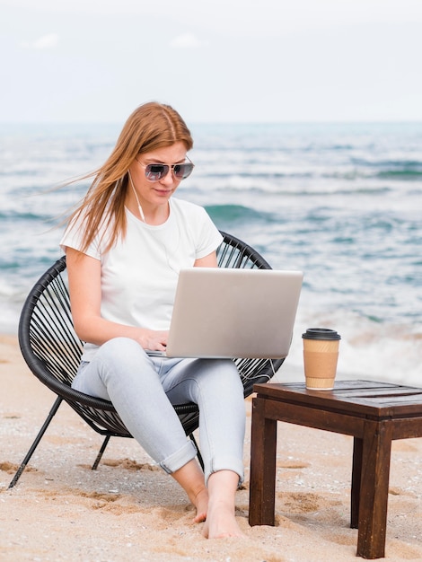 Frau mit Sonnenbrille im Strandkorb, der am Laptop arbeitet