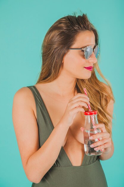 Frau mit Sonnenbrille und kleiner Strohflasche