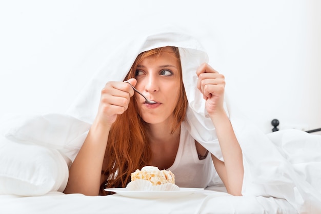 Frau mit süßen Kuchen im Bett