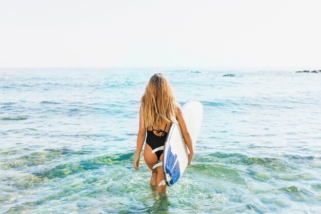 Frau mit Surfbrett am Strand