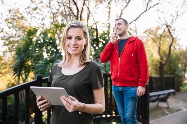 Frau mit Tablette nahe dem Mann, der am Telefon spricht