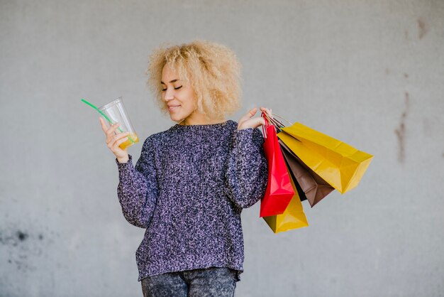 Frau mit Taschen und Getränk