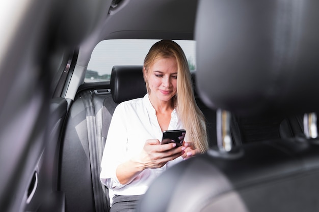 Frau mit Telefon im Autorücksitz