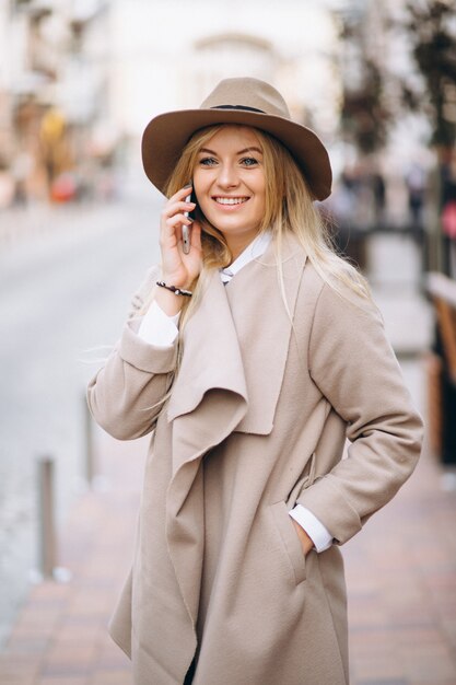 Frau mit Telefon im Hut außerhalb der Straße