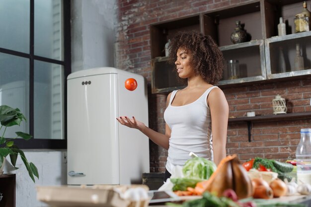 Frau mit Tomate in Ktichen