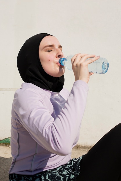 Kostenloses Foto frau mit trinkwasser der purpurroten jacke