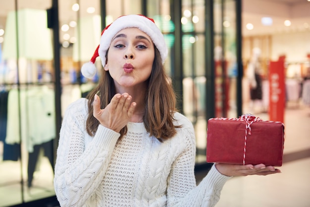 Frau mit Weihnachtsgeschenk, das einen Kuss bläst