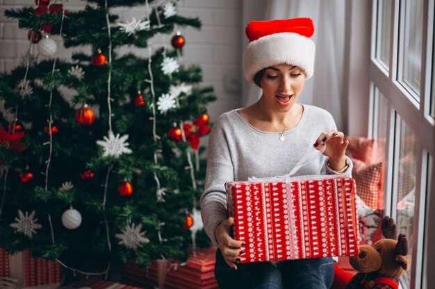 Frau mit Weihnachtsgeschenken durch Weihnachtsbaum