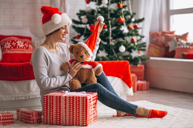 Frau mit Weihnachtsgeschenken durch Weihnachtsbaum