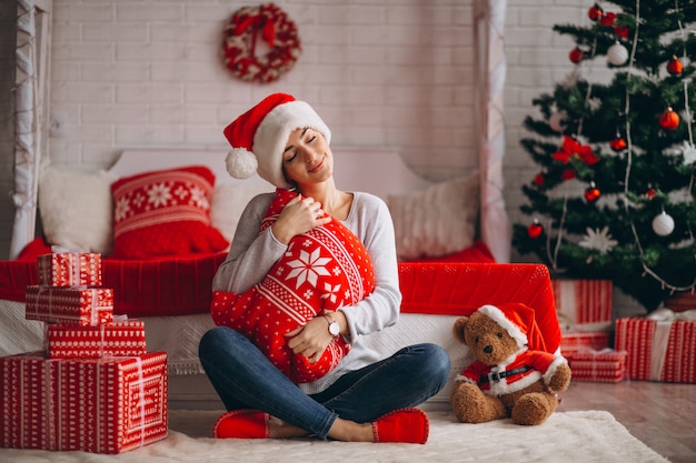 Frau mit Weihnachtsgeschenken durch Weihnachtsbaum