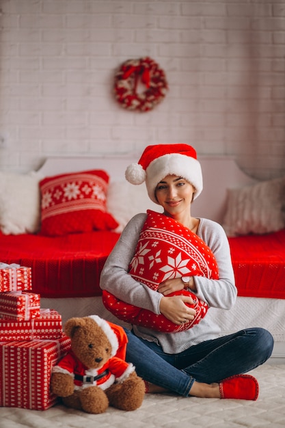 Frau mit Weihnachtsgeschenken durch Weihnachtsbaum