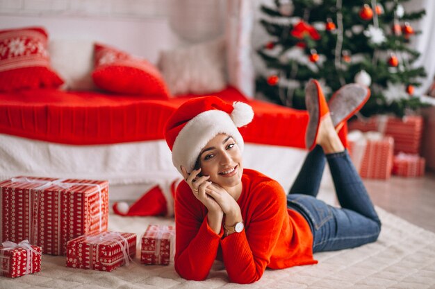 Frau mit Weihnachtsgeschenken durch Weihnachtsbaum