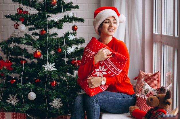Frau mit Weihnachtsgeschenken durch Weihnachtsbaum