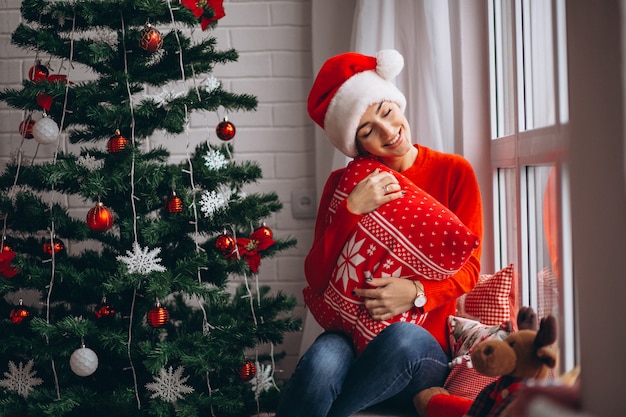 Frau mit Weihnachtsgeschenken durch Weihnachtsbaum