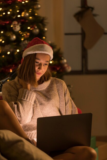 Frau mit Weihnachtsmütze, die Smartphone an Weihnachten betrachtet