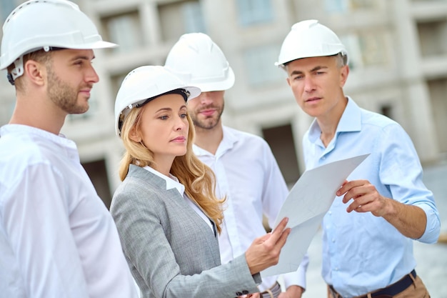 Kostenloses Foto frau mit zeichnung, die ingenieuren und wartenden arbeitern zuhört