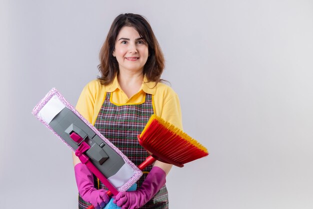 Frau mittleren Alters, die Schürze und Gummihandschuhe trägt, die mit Mops stehen