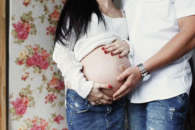 Frau öffnet ihren schwangeren Bauch und Mann legt seine Hand darauf