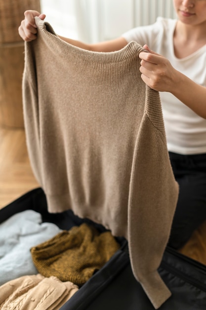 Kostenloses Foto frau packt ihre winterkleidung in ein reisegepäck