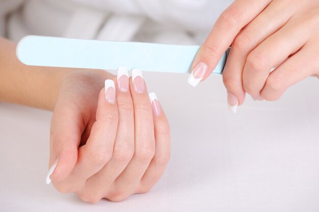 Frau poliert ihre Fingernägel mit einer French Manicure
