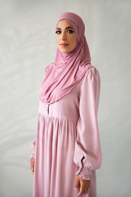 Kostenloses Foto frau posiert mit rosa hijab-seitenansicht