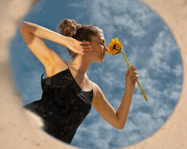 Frau posiert mit rundem Spiegel und Blume