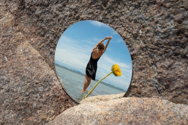 Kostenloses Foto frau posiert mit rundem spiegel und blume