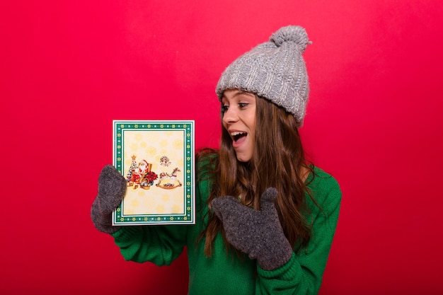 Kostenloses Foto frau posiert mit wintermütze und handschuhen, die ein weihnachtsgeschenk halten