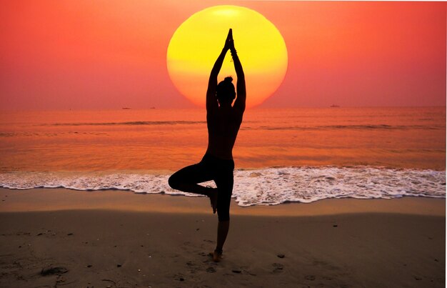 Frau praktizieren Yoga mit der Sonne hinter ihr