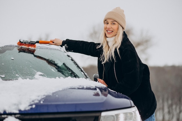 Frau putzt ihr Fensterauto vom Schnee