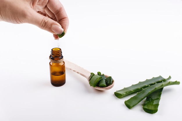 Frau quetscht Saft von der Aloe in einer kleinen braunen Flasche