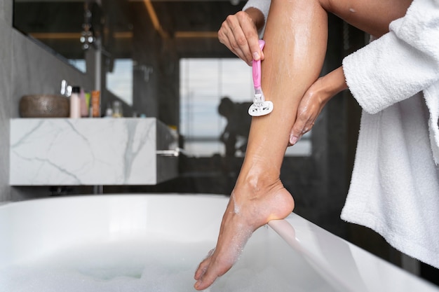 Frau rasiert ihre Verzögerung, bevor sie ein Bad nimmt