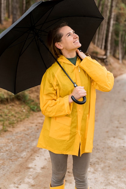 Frau schaut auf, während sie einen Regenschirm über ihrem Kopf hält