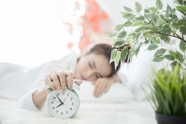 Kostenloses Foto frau schläft im bett, während ihr wecker die frühe zeit zu hause im schlafzimmer zeigt