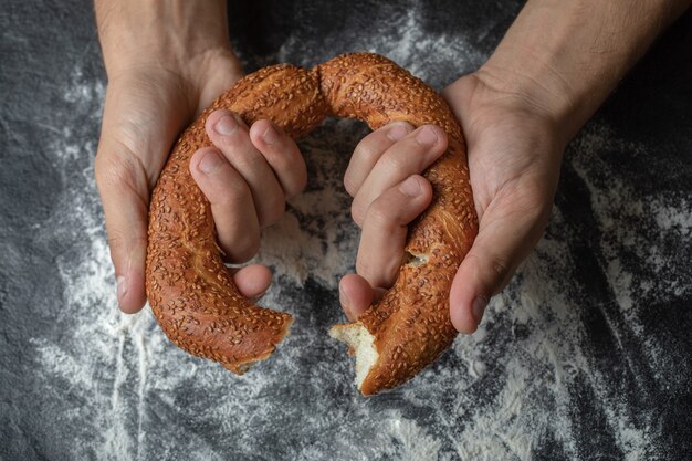 Frau schnitt simit mit der Hand in zwei Hälften.