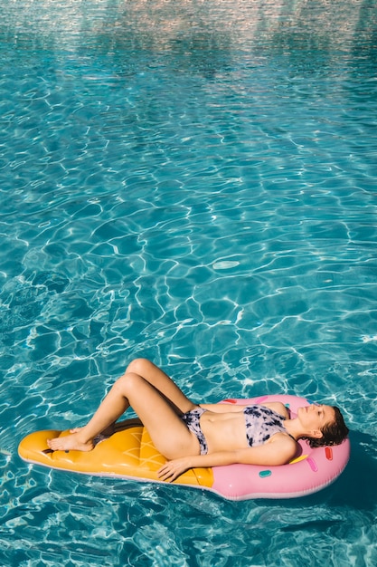 Frau schwimmt auf aufblasbare Matratze im Pool