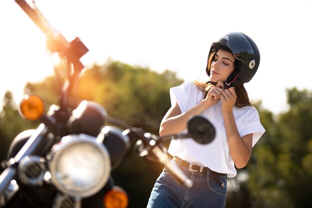 Frau setzt Helm für einen Motorrad-Roadtrip auf