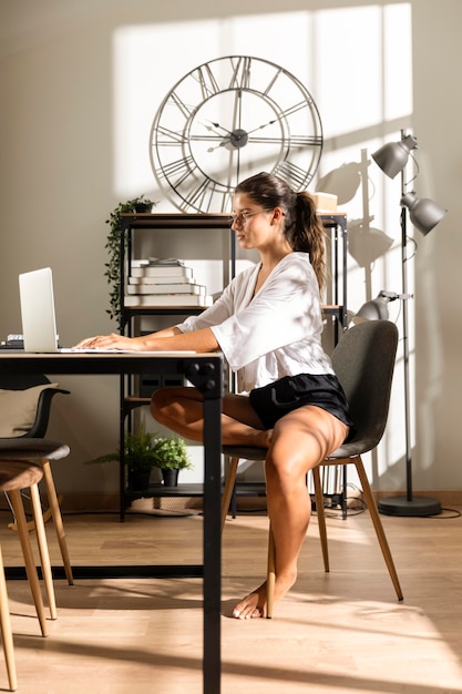 Frau sitzt am Tisch und arbeitet am Laptop