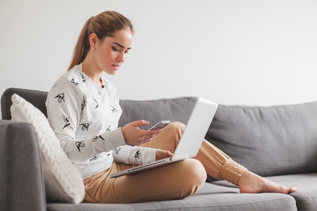 Frau sitzt auf Couch mit Laptop